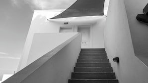 A staircase leading to a door with a security camera and a light fixture on the wall. - Villa Stella (Santorini)