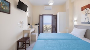 A hotel room with a bed, a desk, a chair, a TV, and a painting. - Villa Stella (Santorini)