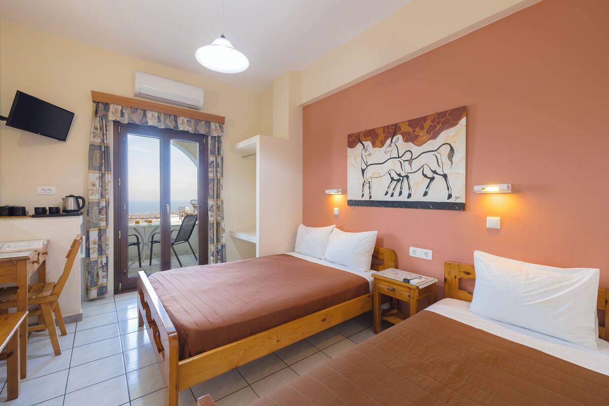 A hotel room with two beds, a desk with a chair, a television, and a painting on the wall.