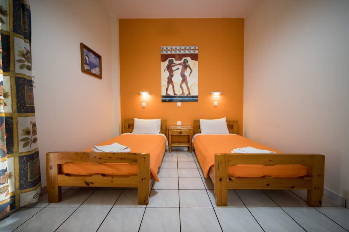 A room with two wooden beds, a mural on the wall, and two wall-mounted lights.