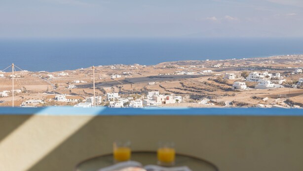 A coastal village with white buildings and wind turbines. - Villa Stella (Santorini)