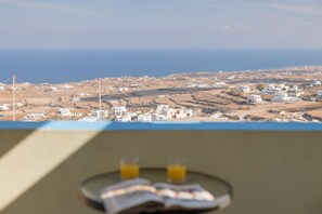 A coastal village with white buildings and wind turbines. - Villa Stella (Santorini)