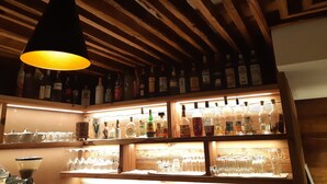 A bar area with wooden beams and shelves stocked with liquor bottles and glasses. - Edelweiss Alpine Nature Hotel (Pinzolo)