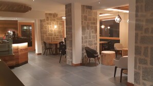 A modern interior with stone walls, a kitchen area, and seating arrangements. - Edelweiss Alpine Nature Hotel (Pinzolo)