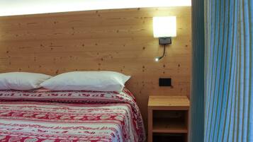Een houten kamer met een bed, kussens en een nachtkastje.