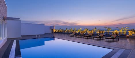 Una piscina al aire libre, sillones reclinables de piscina