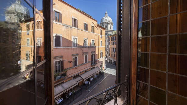 Vista da janela com vista para uma rua e edifícios, incluindo uma estrutura em forma de cúpula à distância.