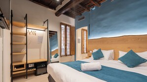 Quarto com cama grande, cabeceira de madeira, roupeiro embutido e pequena cozinha.