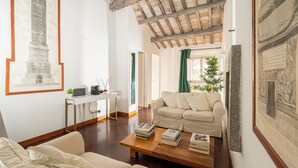 Uma sala de estar com uma mesa de centro de madeira, um sofá branco e uma escrivaninha com um computador.