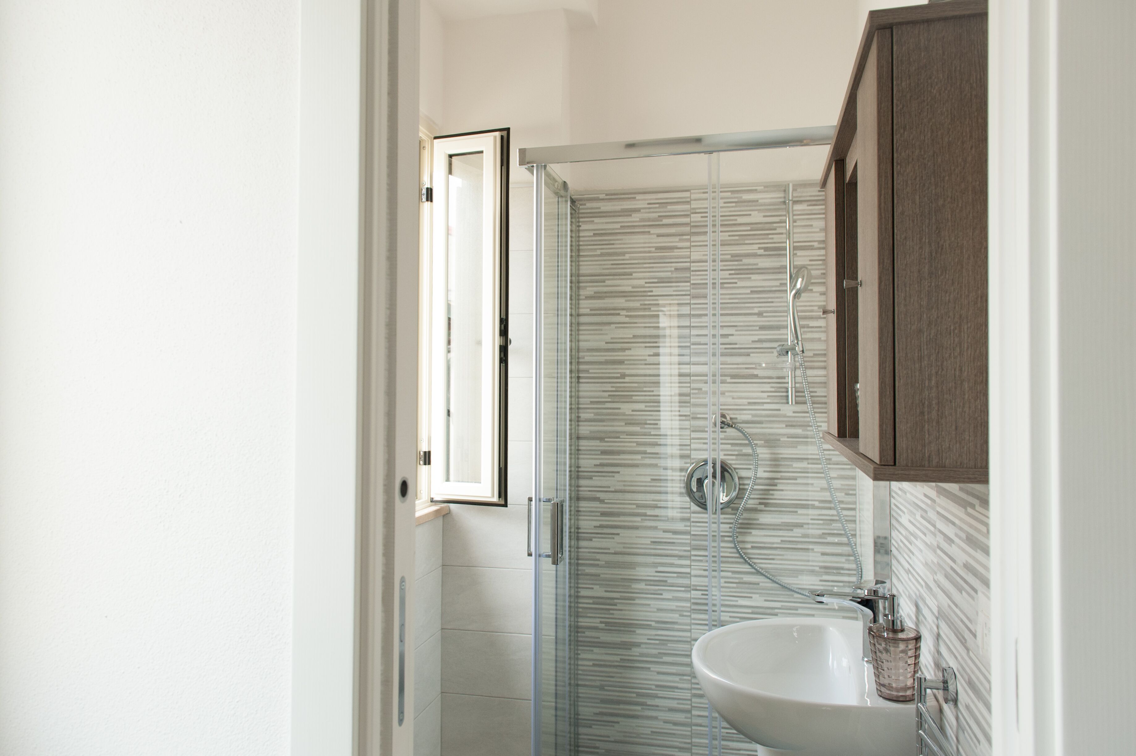 Un baño con cabina de ducha de vidrio, un lavabo y un armario de madera.
