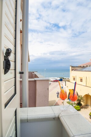 A balcony with a view of the sea and a building with a beige facade.