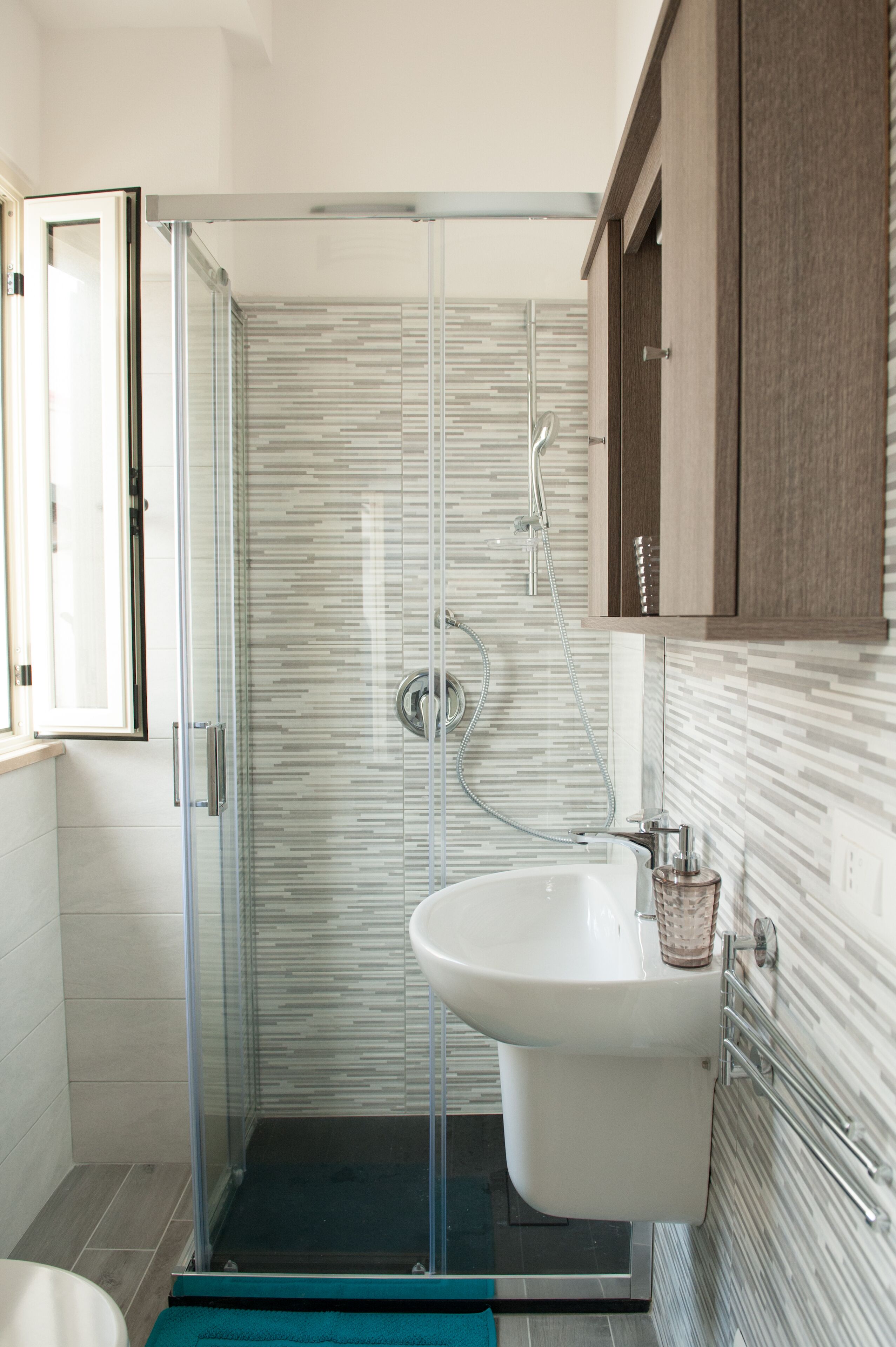 A modern bathroom with a glass-enclosed shower, a white sink, and a wooden cabinet.