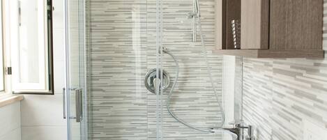 A modern bathroom with a glass-enclosed shower, a white sink, and a wooden cabinet.