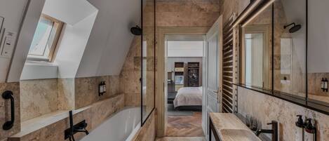 Un baño moderno con una bañera independiente, un espejo grande y un tragaluz.