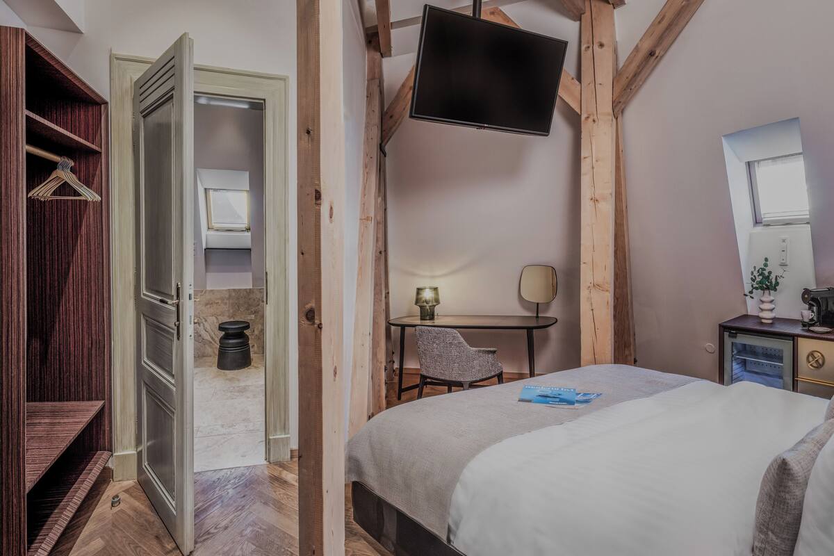 A bedroom with a bed, a desk, a chair, a TV, and a wardrobe.