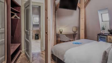 Een slaapkamer met een bed, een bureau, een stoel, een televisie en een kledingkast.