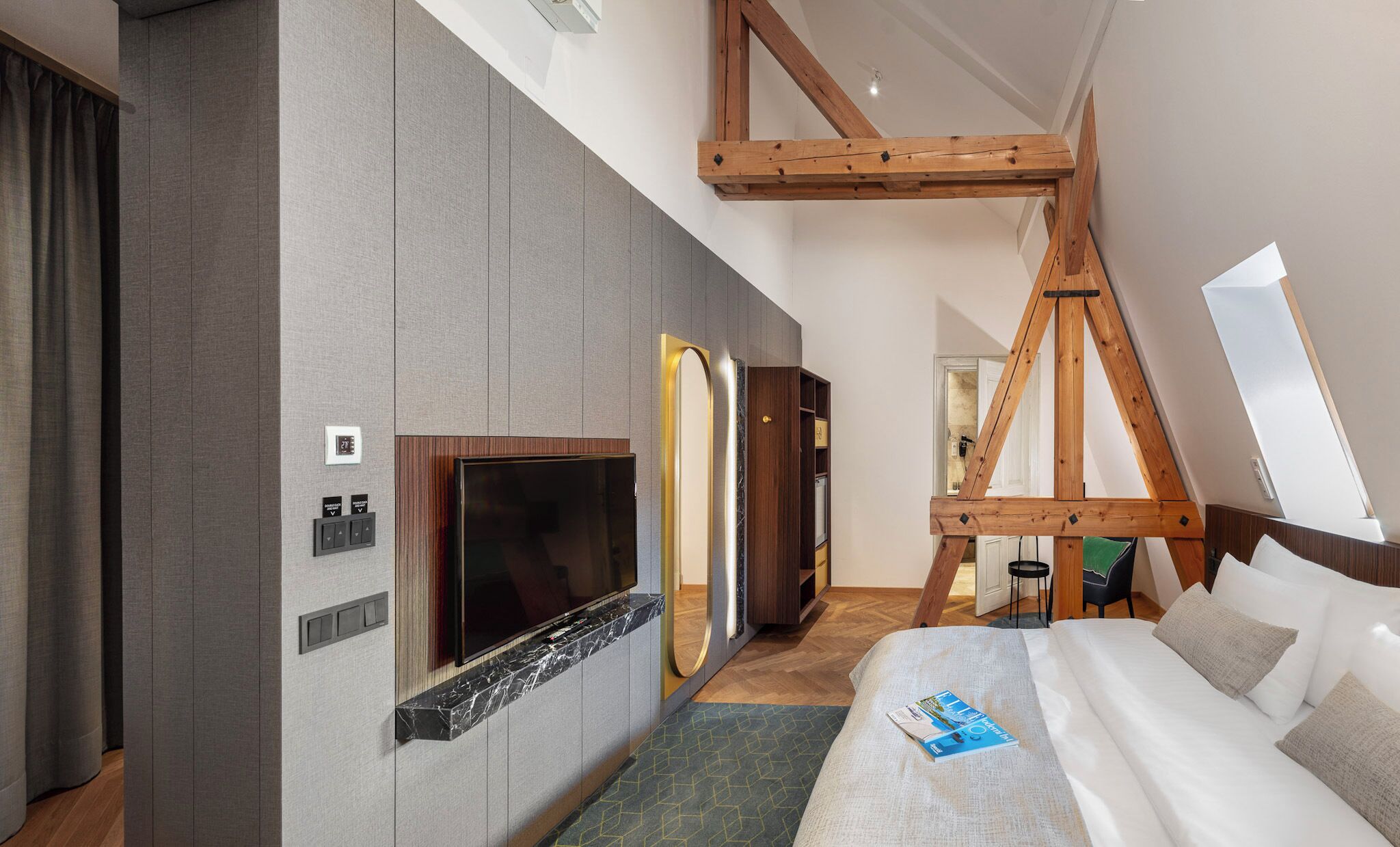Een moderne hotelkamer met een groot bed, een flatscreen televisie, een houten plafond en een grote spiegel.