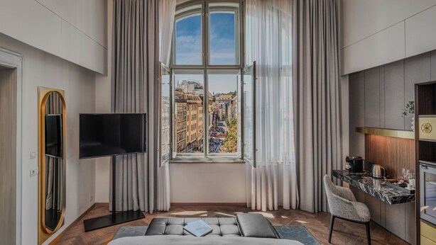 Una habitación de hotel moderna con un ventanal grande, un televisor de pantalla plana, un sofá, un comedor y una kitchenette.