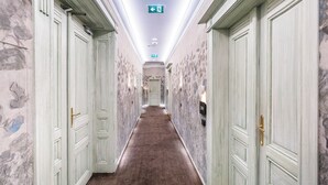 Un pasillo con paredes y puertas de diseño de mármol, suelo alfombrado y una señal de salida en la parte superior.