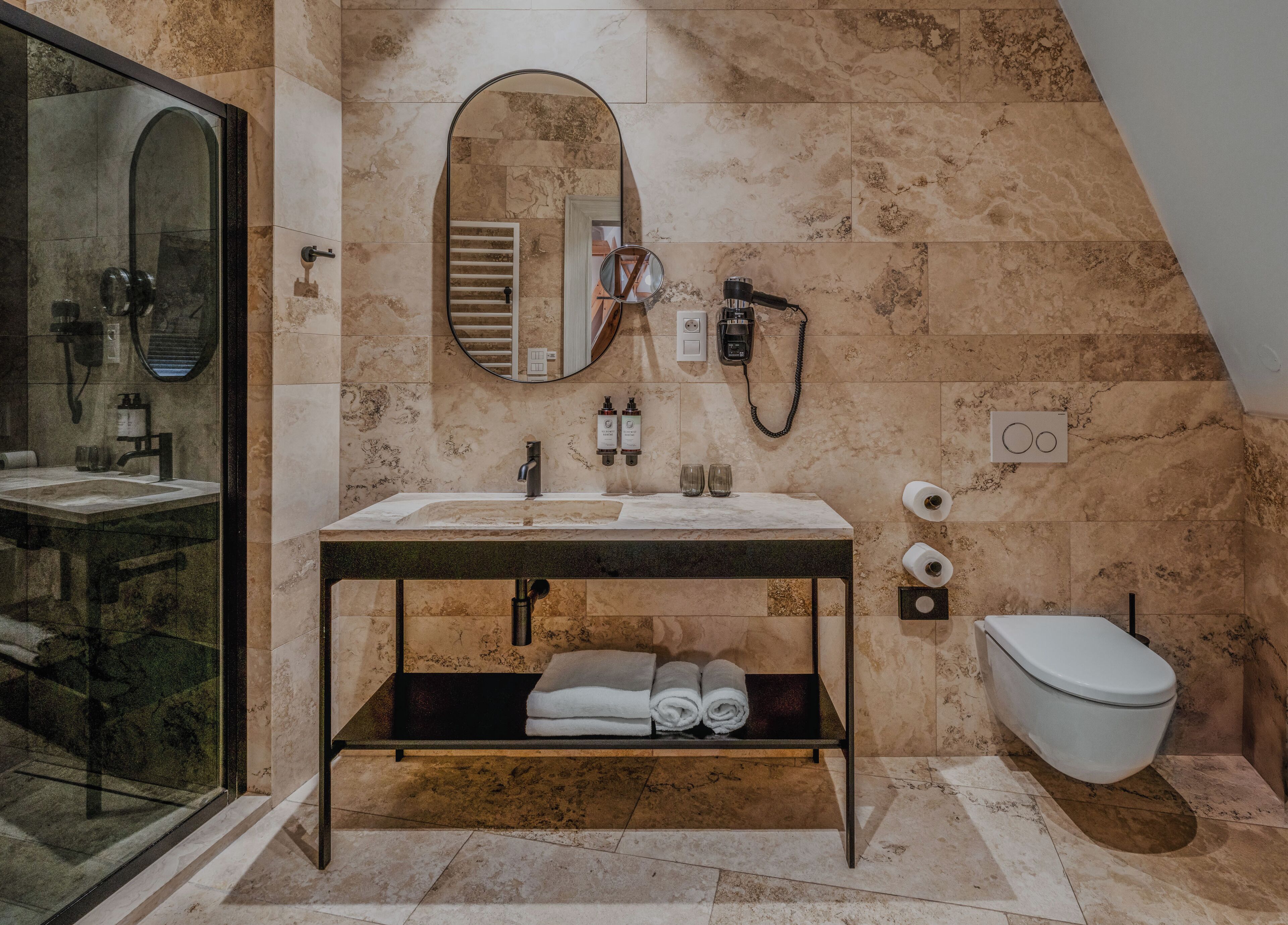 A bathroom with a marble sink, a mirror, a towel rack, a toilet, and a shower area.