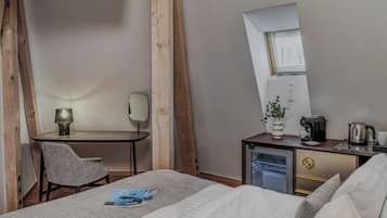 Hotelkamer met een bed, bureau met stoel, kitchenette, spiegel en raam.