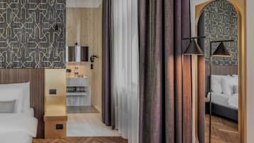 Une chambre d’hôtel avec un lit, une petite kitchenette, un miroir et une vue sur le couloir.