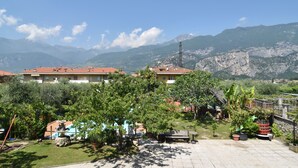 A courtyard with a pool, surrounded by lush greenery and buildings with red roofs. - Agritur Michelotti (Arco)