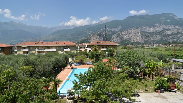 A hotel with a swimming pool surrounded by greenery and mountains in the background. - Agritur Michelotti (Arco)