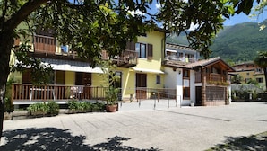 A courtyard with a yellow building, balconies, and potted plants. - Agritur Michelotti (Arco)