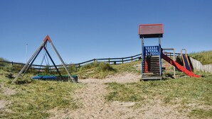 Een speelplaats met een schommel, een glijbaan en een klimconstructie.