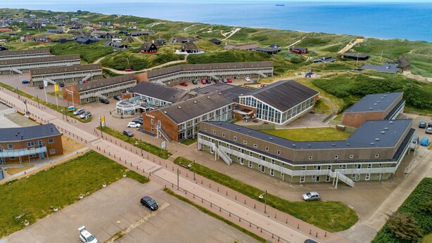 Luchtbeeld van een kustgebied met woonhuizen en een groot complex, inclusief een school en diverse huizen.