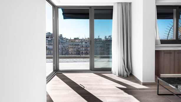 A modern apartment with a large sliding glass door leading to a city view. - Penthouse Level 8 Nilie Hospitality MGMT (Thessaloniki)