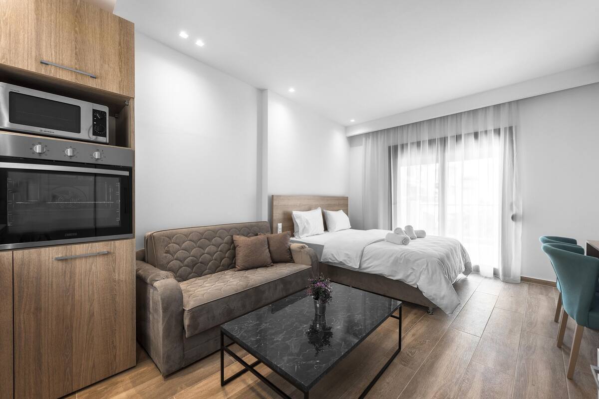 Una habitación de hotel moderna con kitchenette, un sofá, una cama y una mesa de comedor.