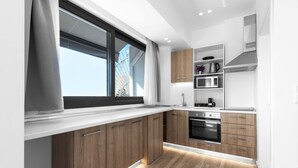 A modern kitchen with wooden cabinets, a built-in oven, and a large window. - Penthouse Level 8 Nilie Hospitality MGMT (Thessaloniki)