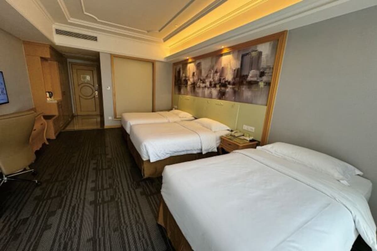 A hotel room with two beds, a desk, and a chair.