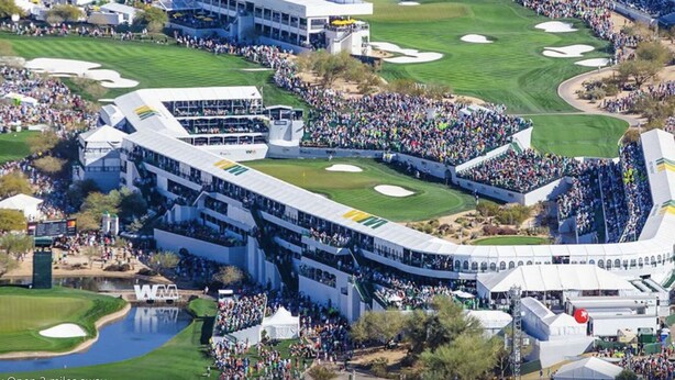 Un campo de golf con gradas para espectadores y un edificio grande con varios niveles de asientos.