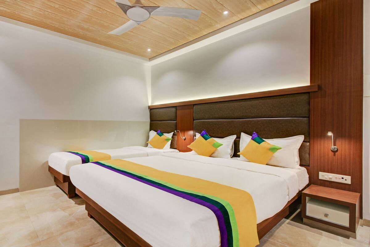 A hotel room with a large bed, a wooden headboard, a nightstand, and a ceiling fan.
