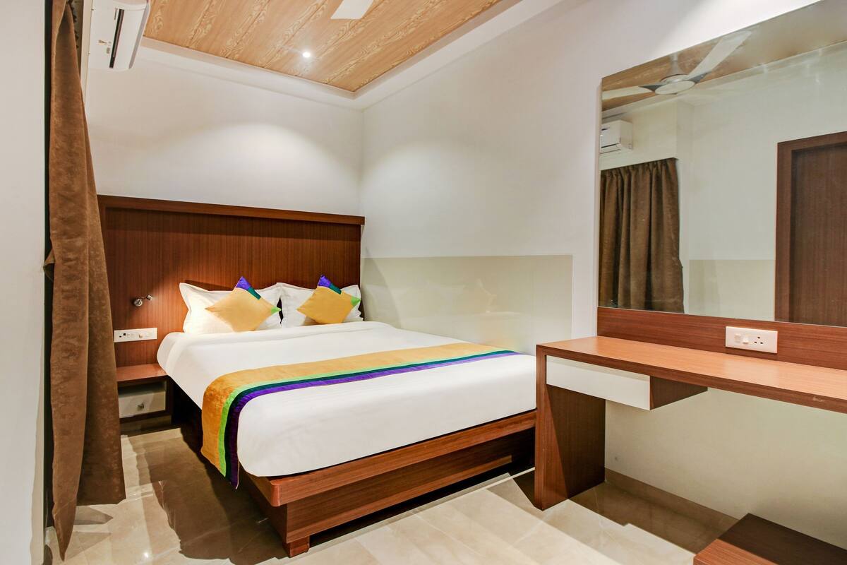 A hotel room with a wooden bed, a bedside table, a mirror, and a nightstand.
