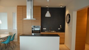 A modern kitchen with a central island, built-in oven, and pendant lighting. - Scandinavian Apartments (Reykjavik)