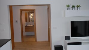 A hallway leading to a bathroom with a mirror, sink, and potted plants on a shelf. - Scandinavian Apartments (Reykjavik)