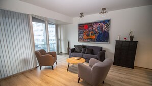 A modern living room with a grey sofa, two armchairs, a wooden coffee table, and a painting on the wall. - Scandinavian Apartments (Reykjavik)