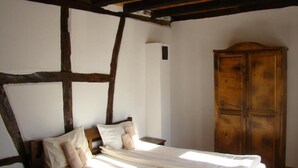 Een slaapkamer met een houten bed, witte wanden en een houten garderobe.