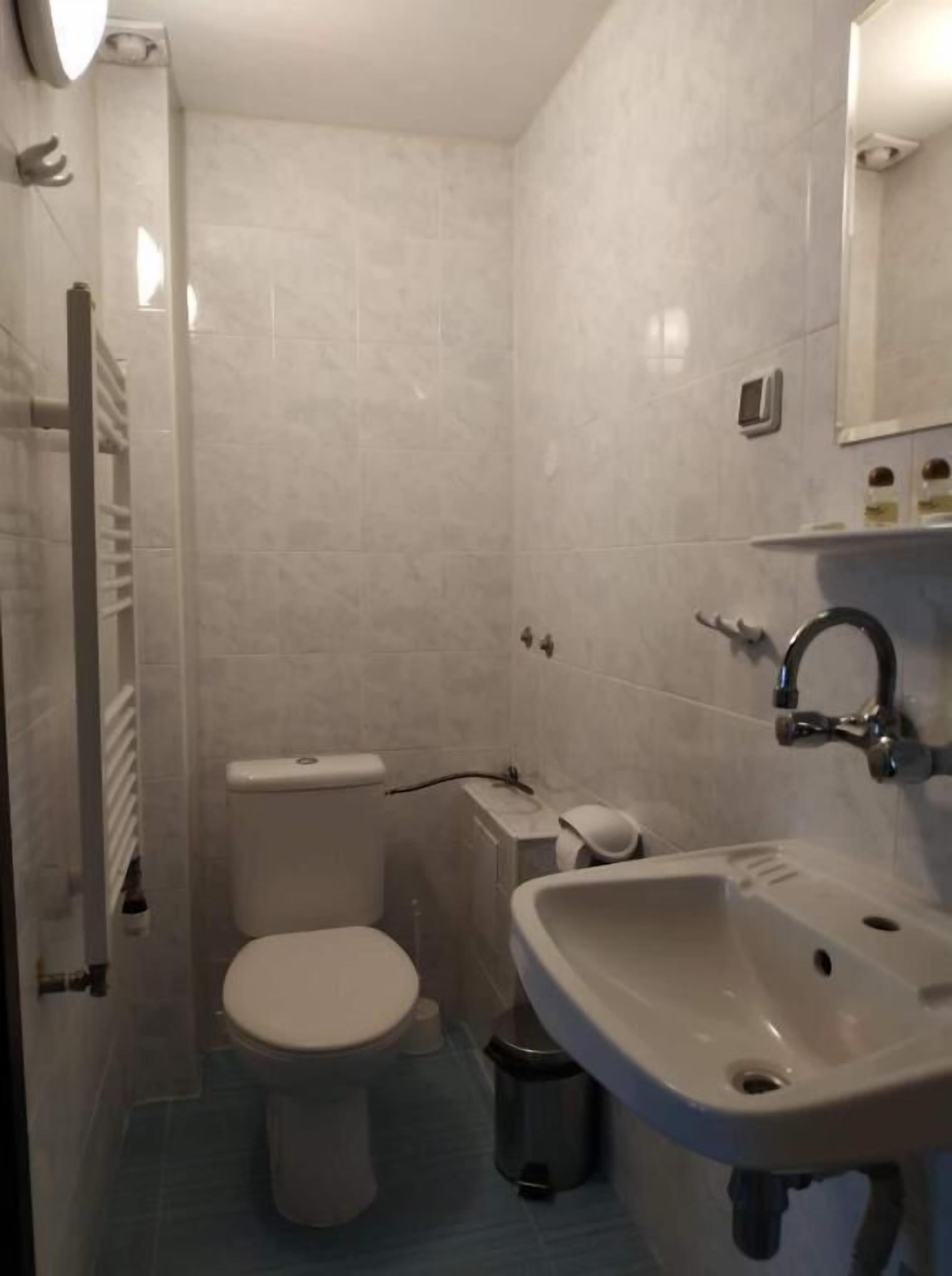 Un baño pequeño y moderno con inodoro, lavabo y espejo.