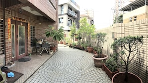 A courtyard with a tiled floor, potted plants, and a table with chairs. - Jeanette Home (New Taipei City)
