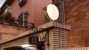 A brick building with a gated entrance, a number sign '13', and a lit sign above the gate. - Jeanette Home (New Taipei City)
