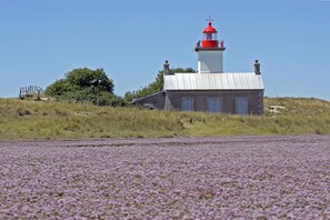 A lighthouse with a red top, a white base, and a small adjacent building. - hotel Les Coutainvillaises (Agon-Coutainville)