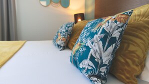 A neatly made bed with floral pillows and a yellow blanket.