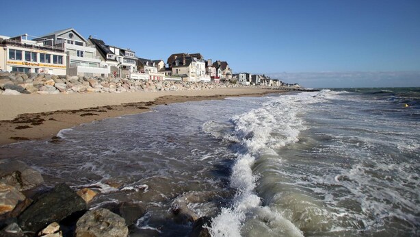 A beach with a row of houses and a restaurant named "Bar Leucum".