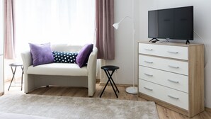 Una sala de estar moderna con un sofá, un televisor sobre un mueble de madera, una mesita auxiliar y una lámpara de pie.