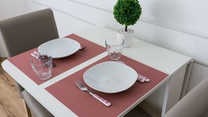Una mesa de comedor dispuesta con platos, cubiertos y un vaso de agua.